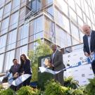 A group of four people cut a ribbon outside of Aggie Square